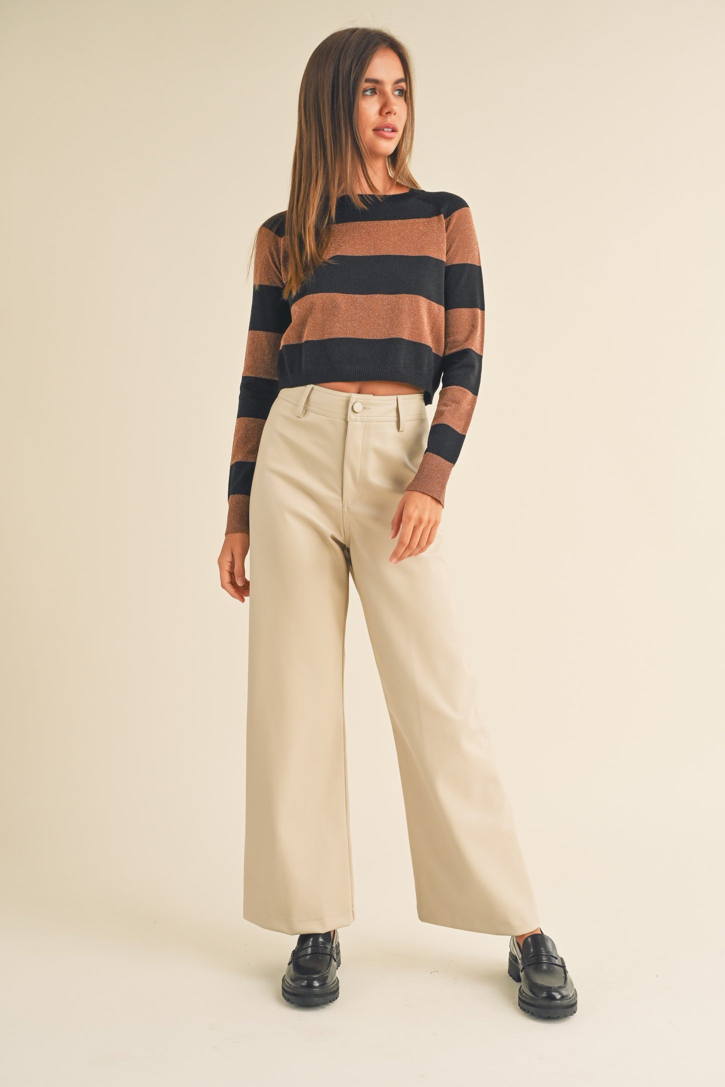 woman wearing a brown and black striped sweater with beige wide-leg pants and black shoes