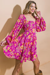 woman wearing a bright pink floral print mini dress with puff sleeves and a square neckline