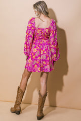 woman wearing a pink floral mini dress with puff sleeves and smocked back, paired with brown cowboy boots