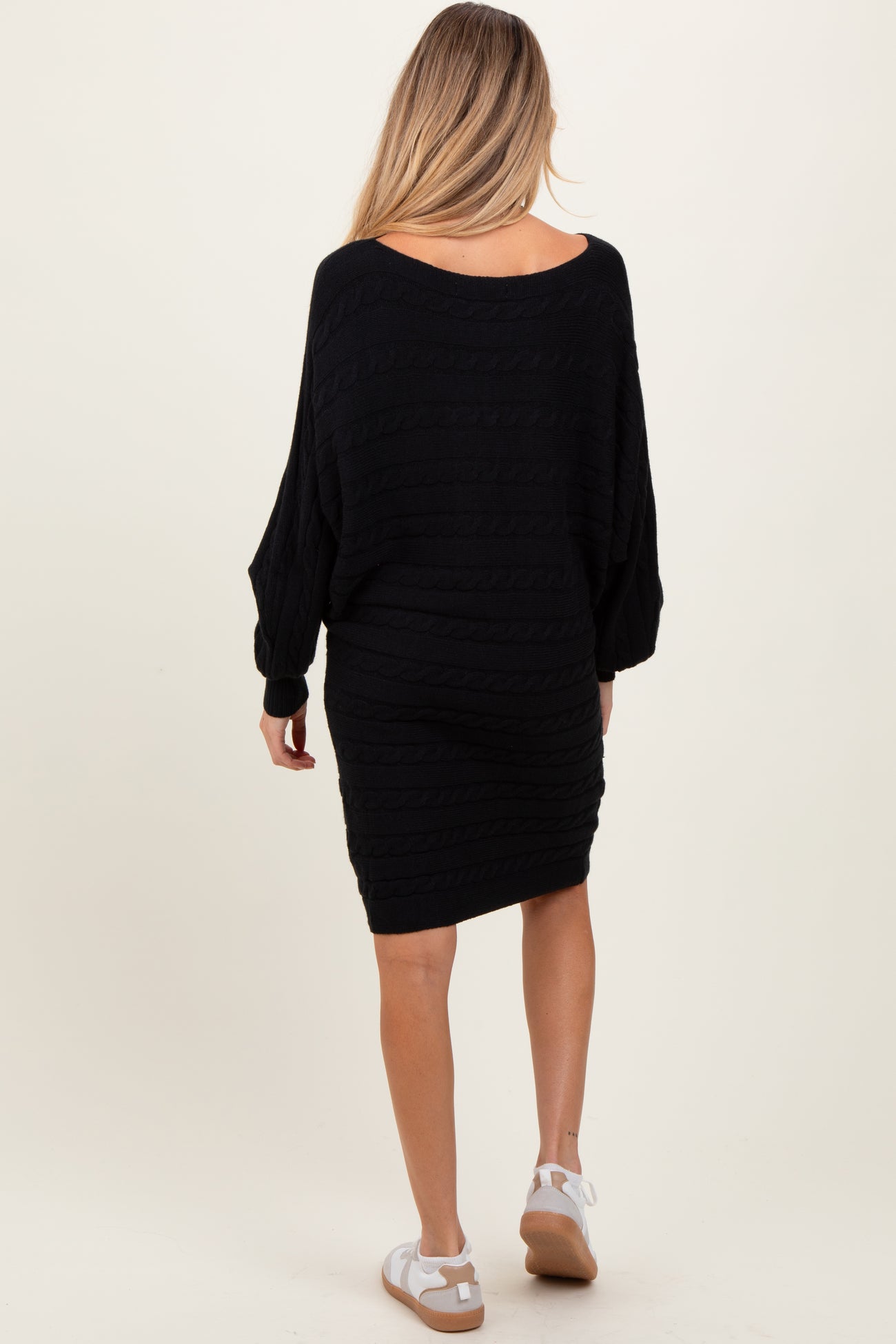 woman wearing a black maternity sweater dress with a relaxed fit and long sleeves, seen from the back
