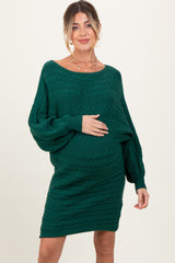 woman wearing a green cable knit maternity dress and holding her baby bump