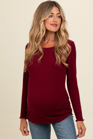 woman wearing a burgundy long sleeve maternity top with ruffled hemline and visible baby bump