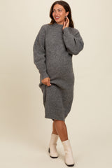 woman wearing a cozy gray ribbed maternity sweater dress, gently cradling her baby bump