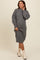woman wearing a cozy gray ribbed maternity sweater dress, gently cradling her baby bump