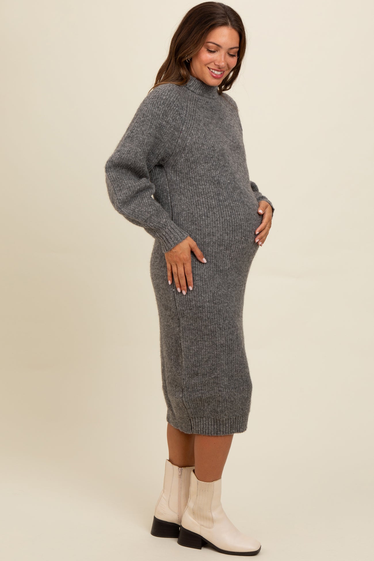 woman wearing a grey knitted maternity dress with side slits and a baby bump visible