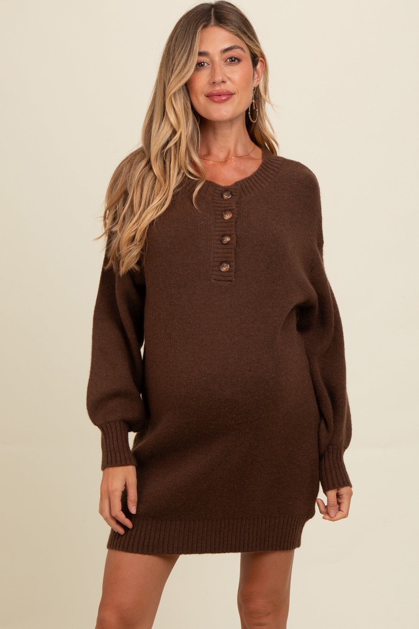 woman wearing a brown maternity sweater dress with buttons and balloon sleeves, showing her baby bump
