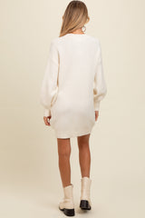 woman wearing an ivory oversized maternity sweater dress with balloon sleeves, viewed from the back