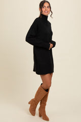 woman wearing a black turtleneck sweater dress with long sleeves and knee-high beige boots