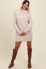 woman wearing a light beige oversized turtleneck sweater dress and brown knee-high boots
