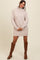 woman wearing a light beige oversized turtleneck sweater dress and brown knee-high boots