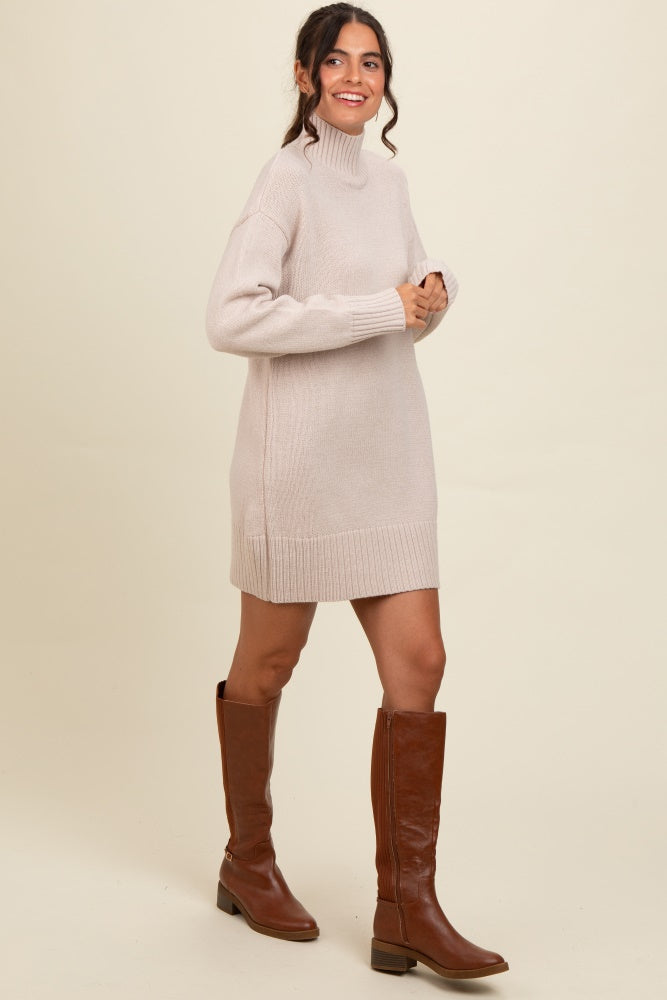 woman wearing a beige knit turtleneck sweater dress with long sleeves and knee-high brown boots