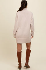 woman wearing a light pink oversized knit sweater dress with long sleeves and knee-high brown boots
