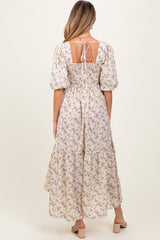 woman wearing a floral maxi maternity dress with puff sleeves and a tie back detail