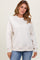 woman wearing a light beige long sleeve sweatshirt with ribbed cuffs and hem, paired with blue jeans