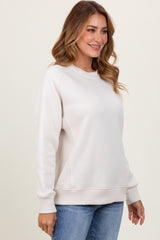 woman wearing a light beige long sleeve sweatshirt with ribbed details and a relaxed fit