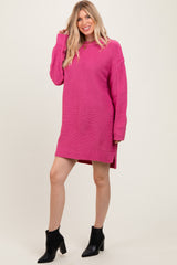 woman wearing a bright pink oversized sweater dress with side slits and long sleeves, paired with black ankle boots