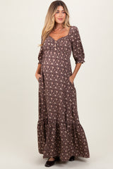 woman wearing a brown floral maternity maxi dress with puff sleeves and pockets, showcasing her baby bump