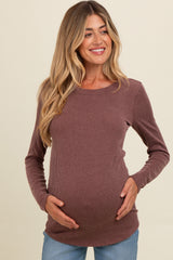 woman wearing a mauve ribbed maternity top and holding her baby bump