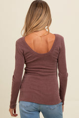 woman wearing a mauve ribbed maternity top with a scoop back and long sleeves, showing off her baby bump