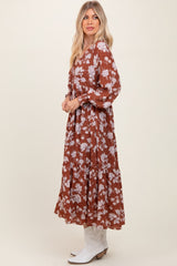 woman wearing a brown floral maxi dress with long sleeves and a flowing skirt, styled with white cowboy boots