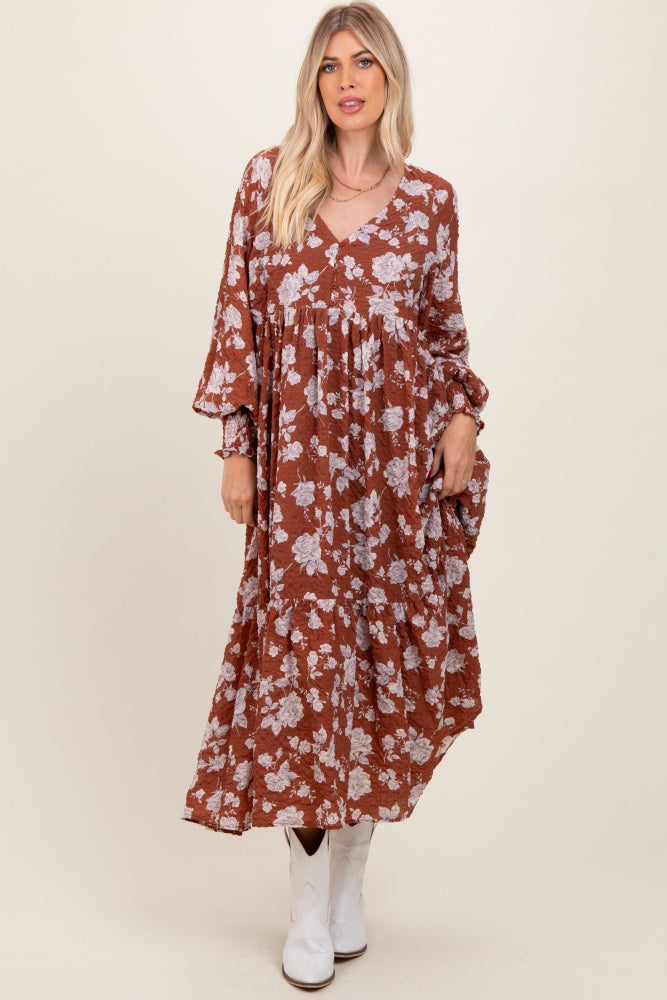 woman wearing a rust floral maxi dress with long sleeves and a v-neckline, paired with white ankle boots