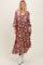 woman wearing a rust floral maxi dress with long sleeves and a v-neckline, paired with white ankle boots