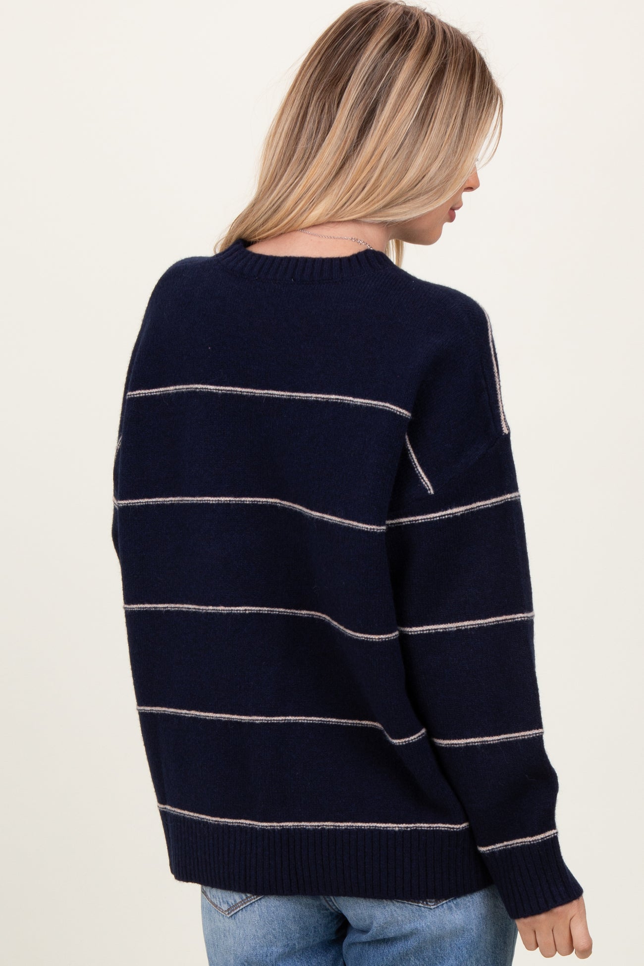 woman wearing a navy blue striped sweater with a relaxed fit and crew neck, shown from the back
