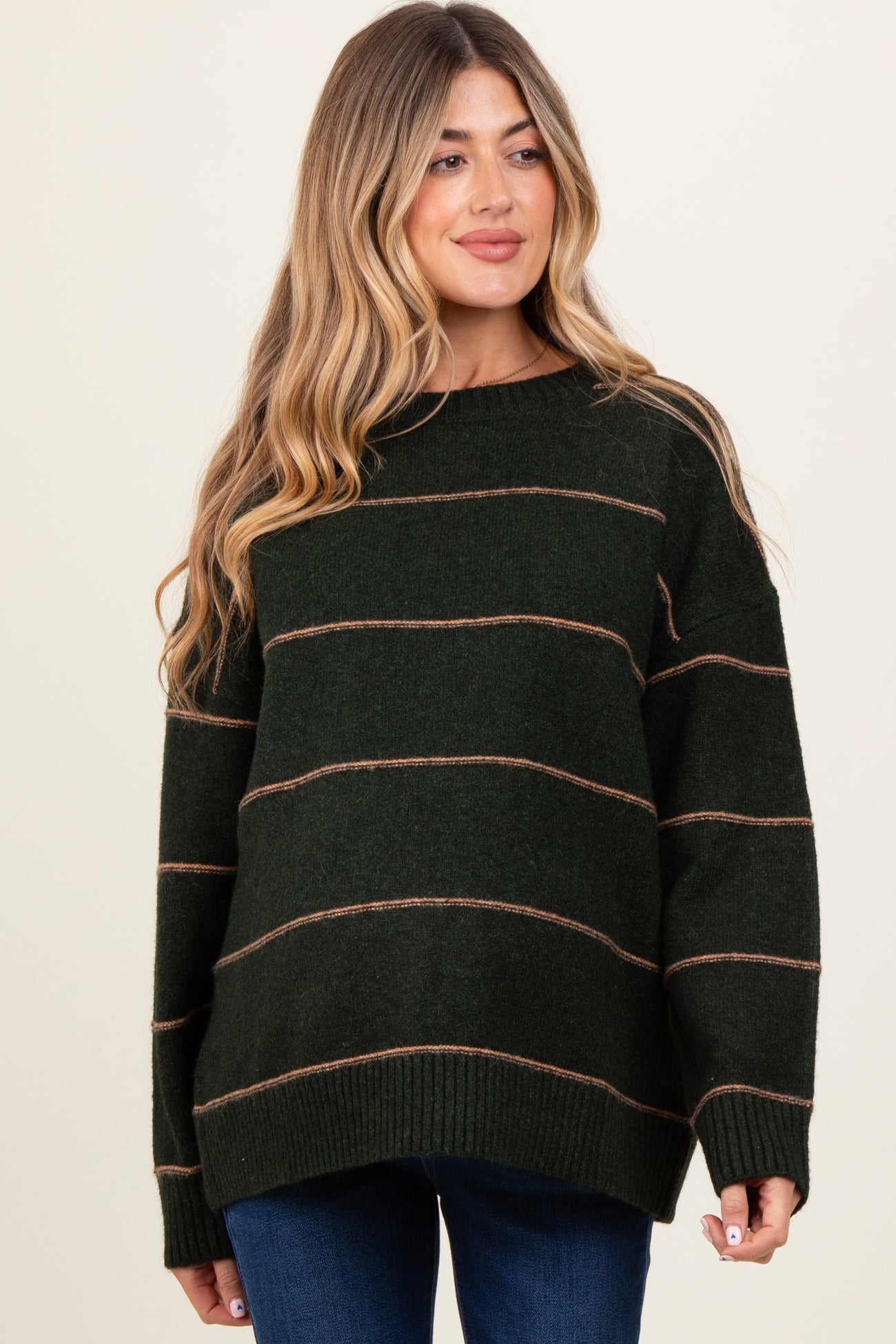woman wearing a dark green striped maternity sweater with long sleeves and a relaxed fit