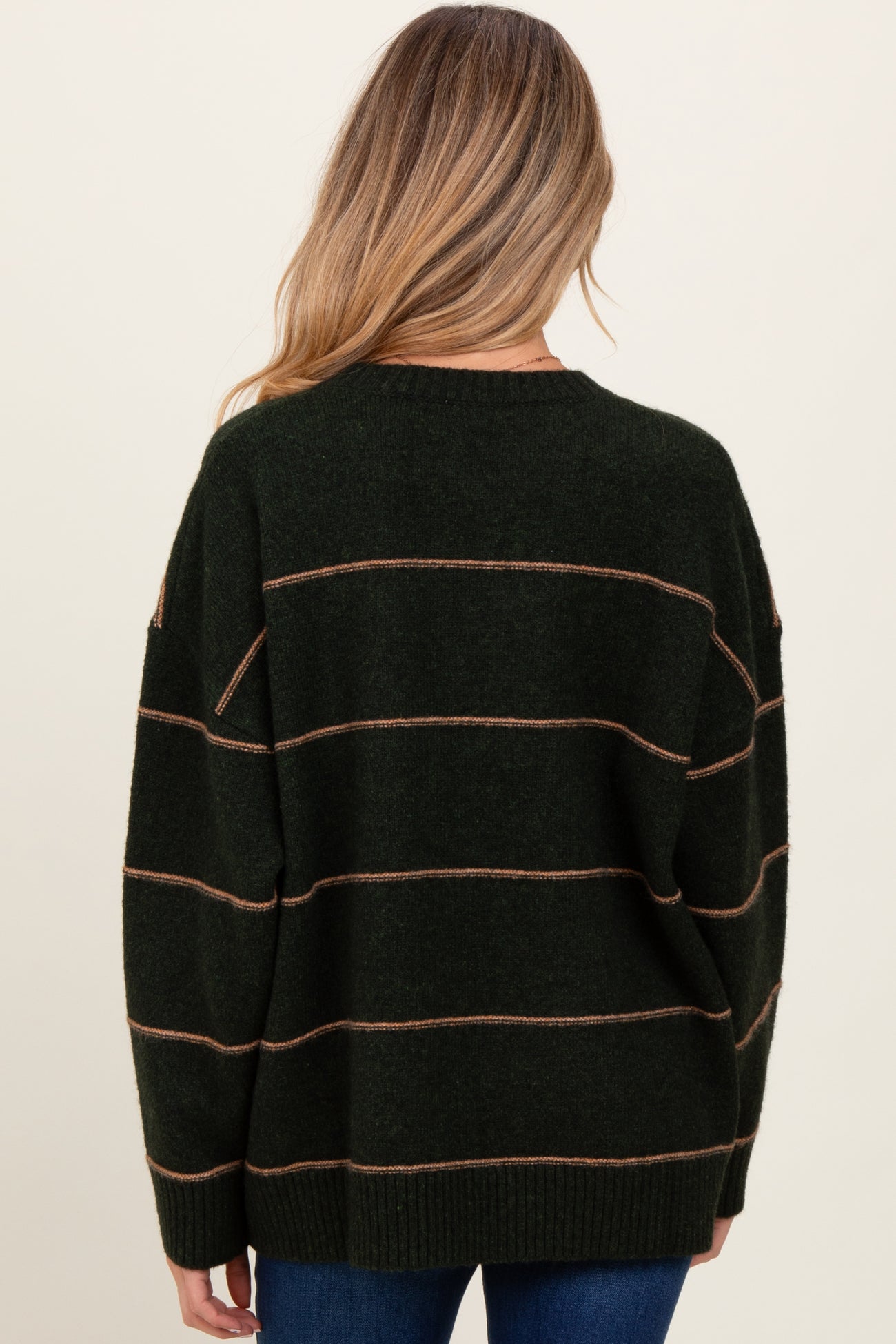 woman wearing a dark green maternity sweater with tan stripes, showing the back view and loose fit