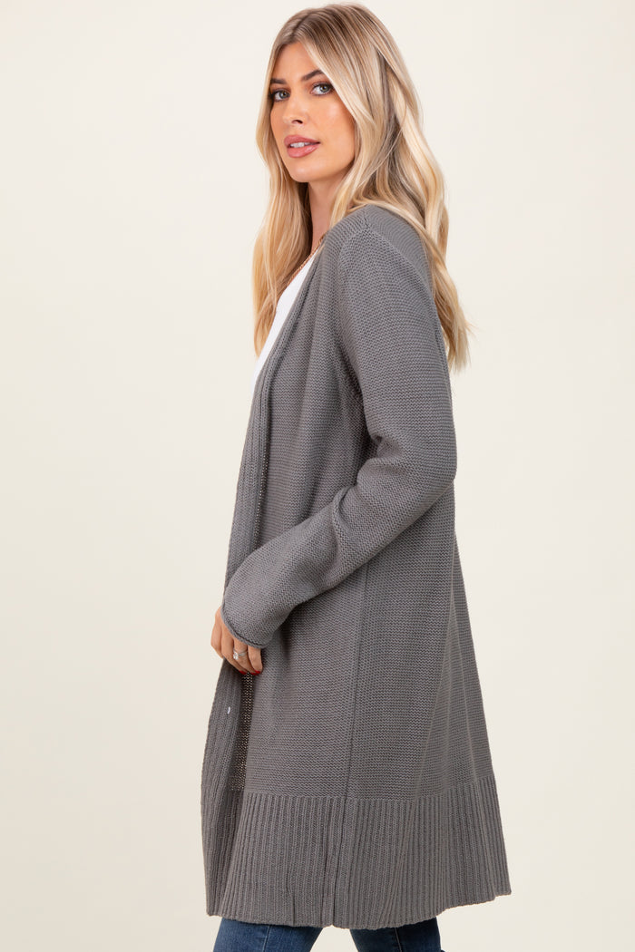 woman wearing a long gray cardigan with a textured finish and open front, styled with a white top and jeans