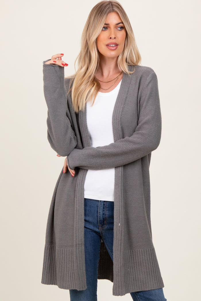 woman wearing a long grey knit cardigan over a white top and blue jeans