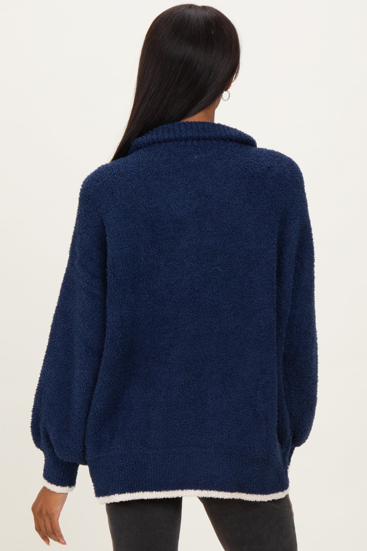woman wearing a navy blue fuzzy sweater with a high collar and balloon sleeves, showing the back view