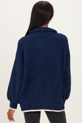 woman wearing a navy blue fuzzy sweater with a high collar and balloon sleeves, showing the back view