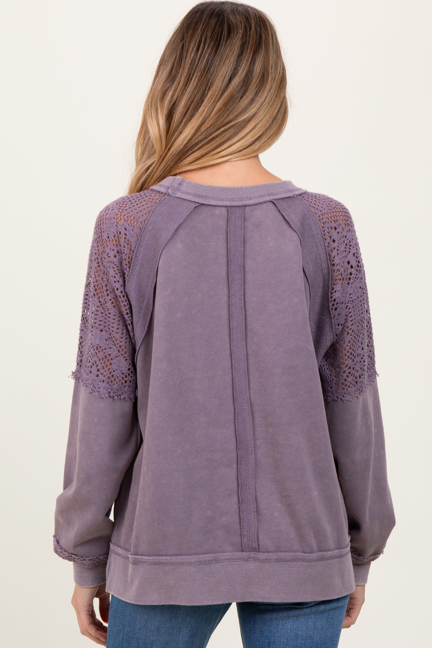 woman wearing a lavender maternity sweatshirt with detailed lace sleeves and a relaxed fit, view from the back