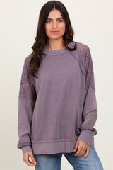 woman wearing a lavender oversized sweatshirt with lace details on the shoulders and ribbed cuffs, paired with blue jeans
