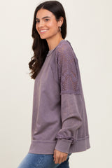 woman wearing a purple long sleeve sweatshirt with lace details on the shoulders and sleeves