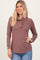 woman wearing a mauve long sleeve waffle knit top with a ruffled neckline and button details