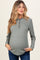 woman wearing a green long sleeve maternity top with button details and a visible baby bump