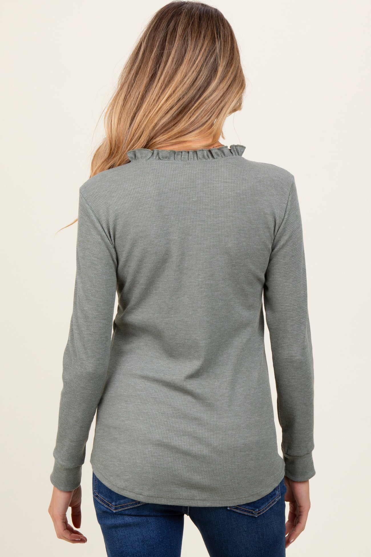 woman wearing a green long sleeve maternity top with ruffle detail at the neckline and back view visible