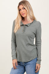 woman wearing a green ruffle collar long sleeve henley top with button details and paired with light blue jeans