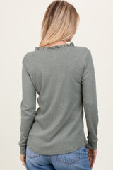 woman wearing a green long sleeve ribbed top with ruffle detail on the neckline, seen from the back