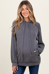 woman wearing a gray ribbed maternity hoodie with a front pocket and drawstring hood, smiling at the camera