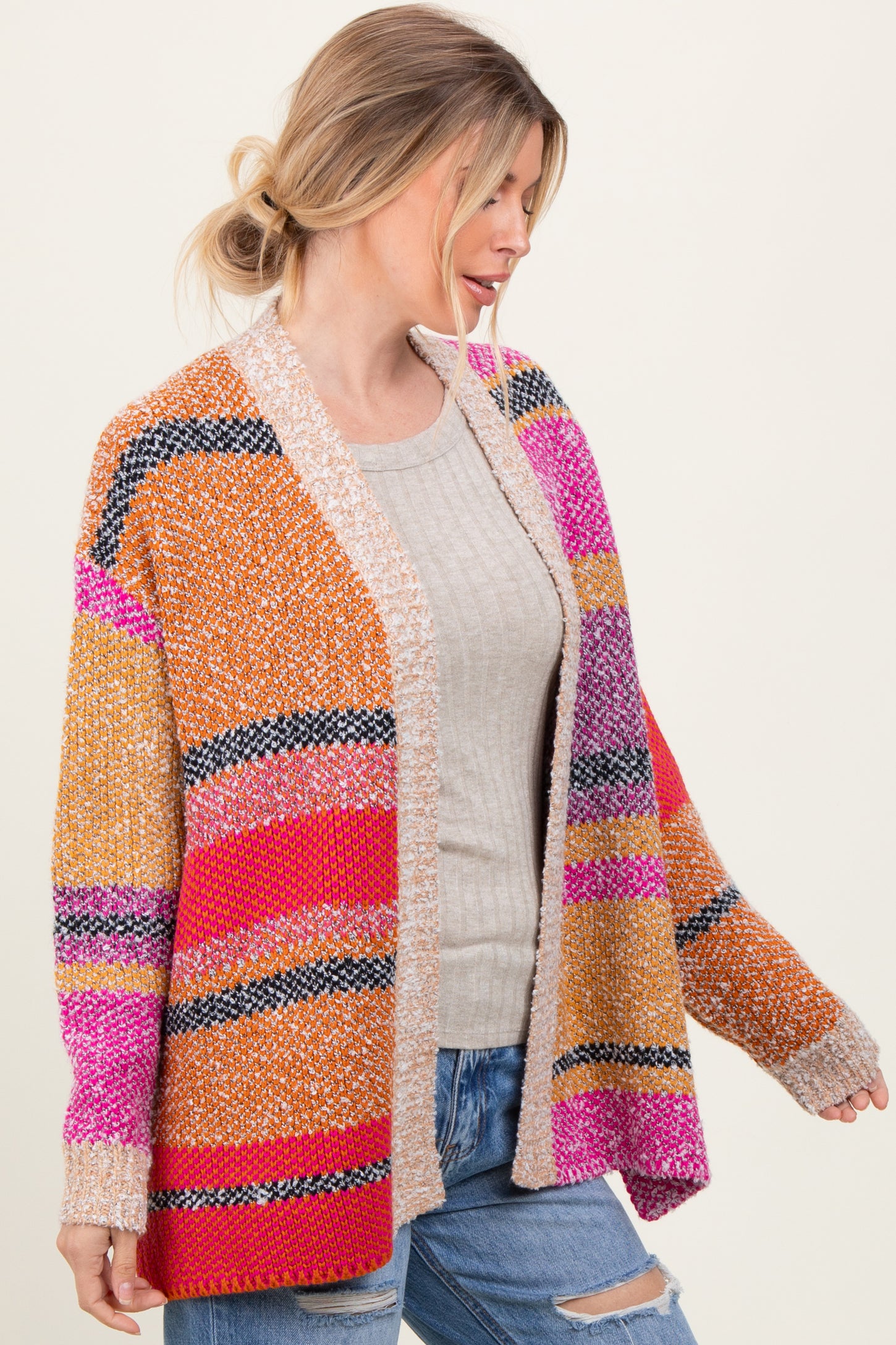 woman wearing a multicolored striped cardigan over a light gray sweater and blue jeans