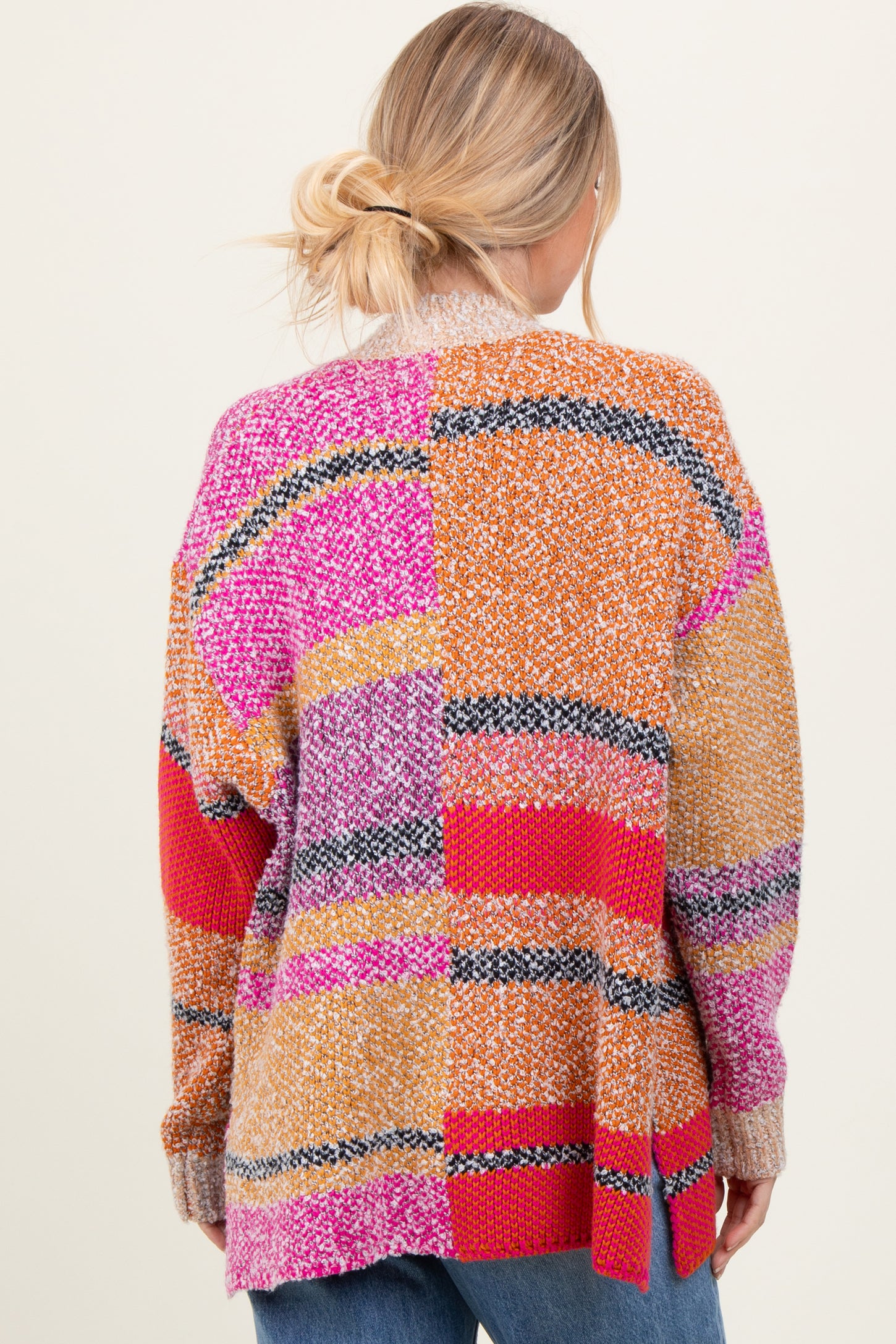 woman wearing a multicolored oversized sweater with a patchwork design and a cozy knit texture