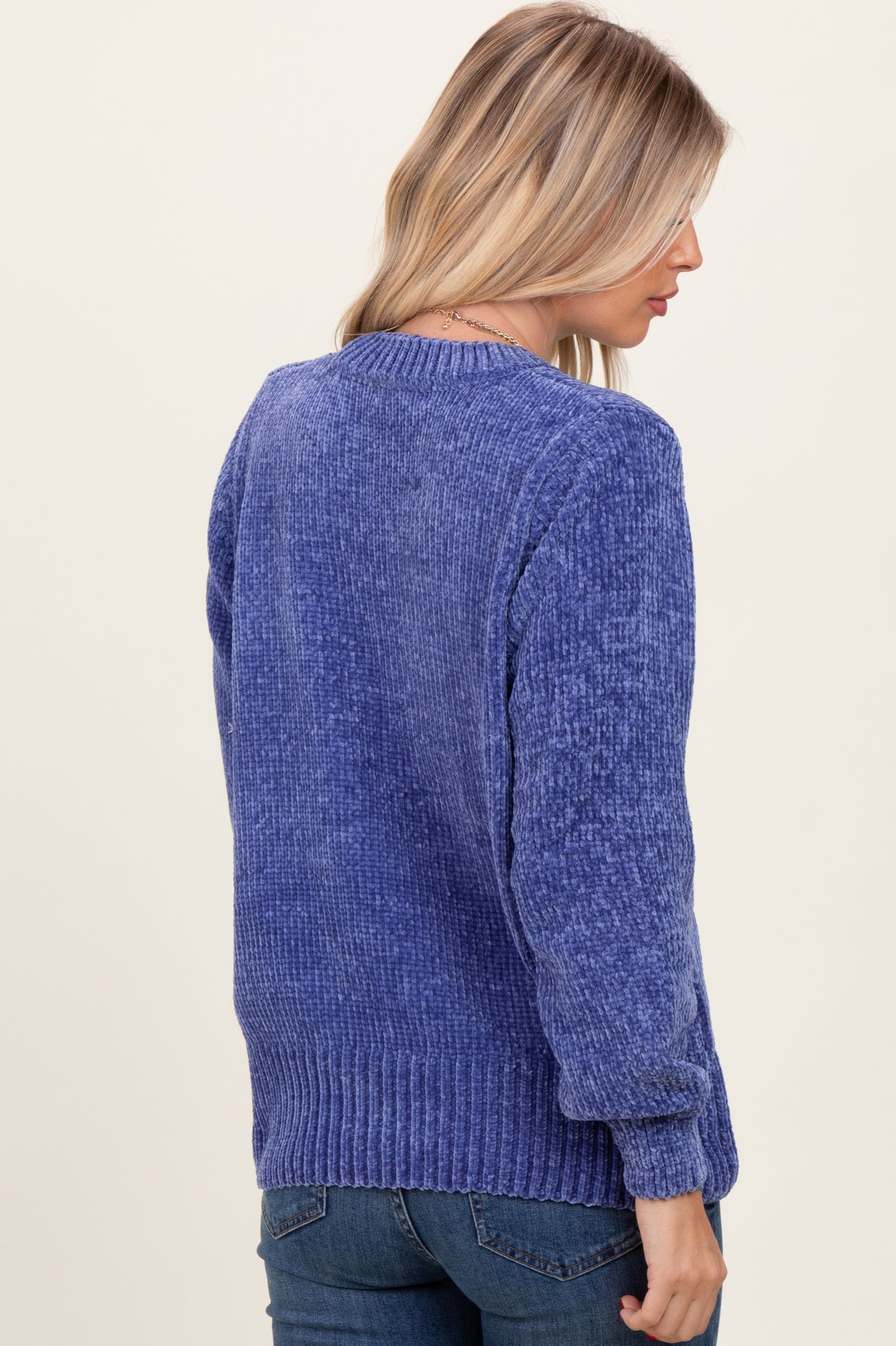 woman wearing a textured purple sweater with a crew neck and ribbed hem, seen from the back