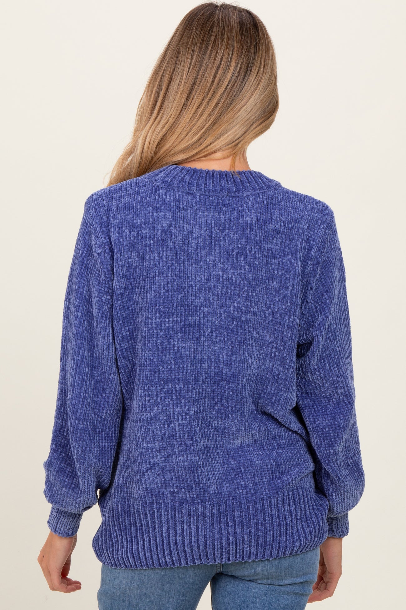 woman wearing a blue maternity sweater with a loose fit and ribbed hem, showing the back view