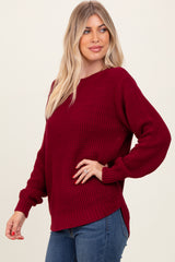 woman wearing a burgundy textured knit sweater with balloon sleeves and a relaxed fit paired with blue jeans