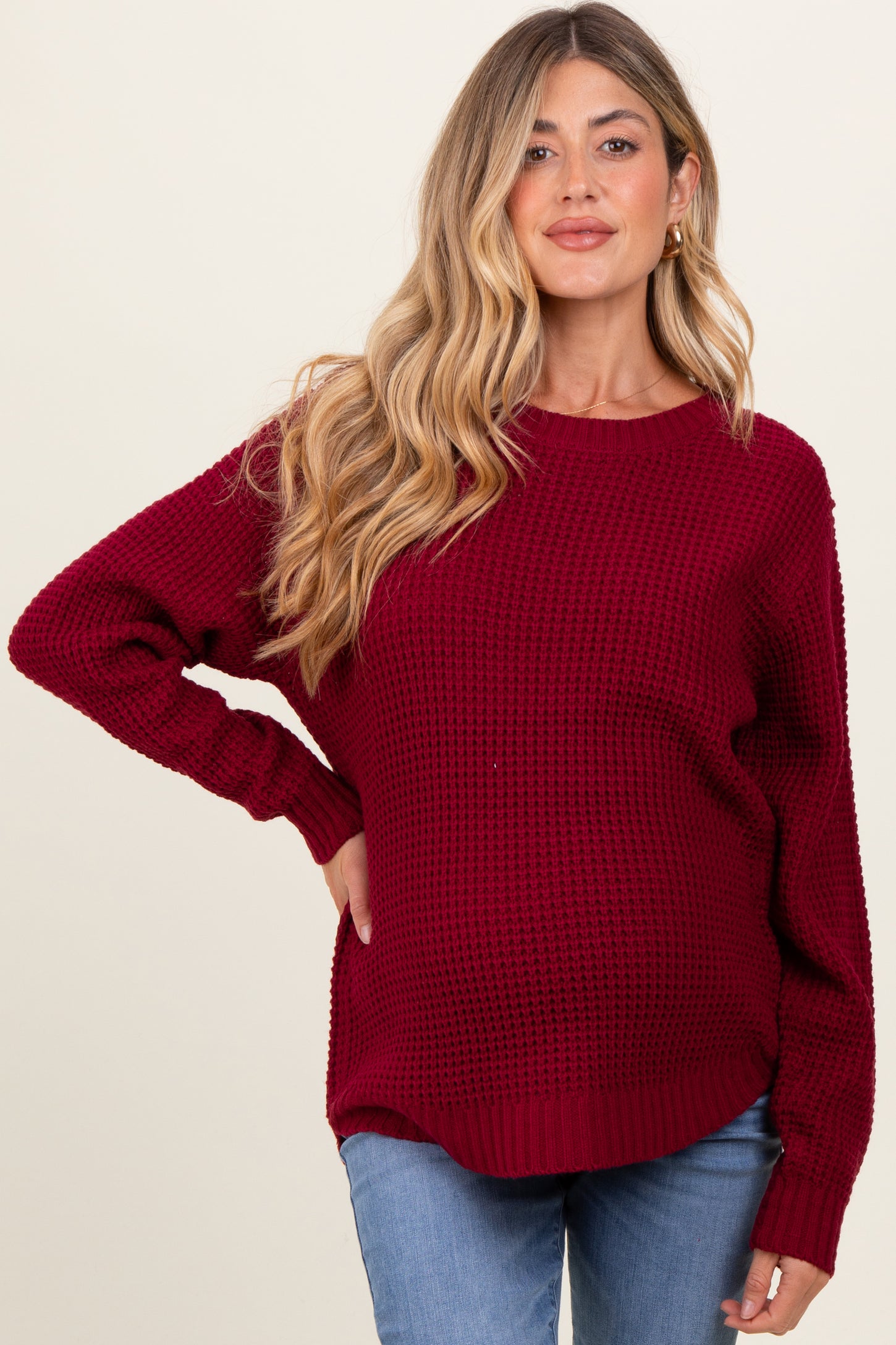 woman wearing a burgundy maternity sweater with a textured knit and relaxed fit, showcasing her baby bump