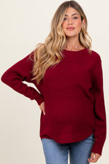 woman wearing a burgundy maternity sweater with a textured knit and relaxed fit, showcasing her baby bump