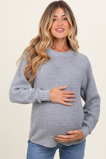 woman wearing a grey knitted maternity sweater and holding her baby bump